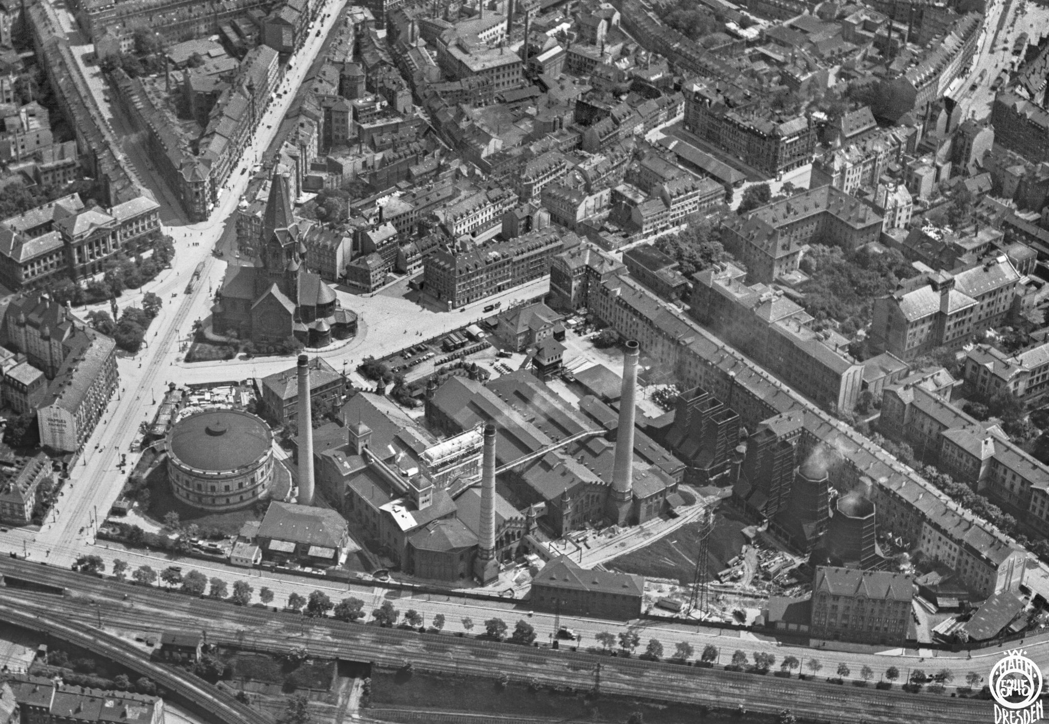 Foto: Luftaufnahme des Heizkraftwerks Mitte in Dresden mit Schornsteinen und umliegender Stadt.